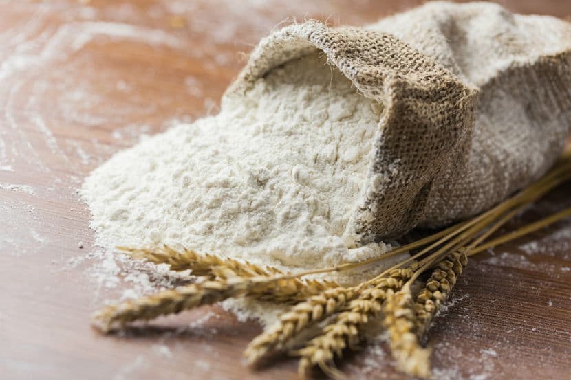 Flour spilling from a burlap sack with wheat stalks